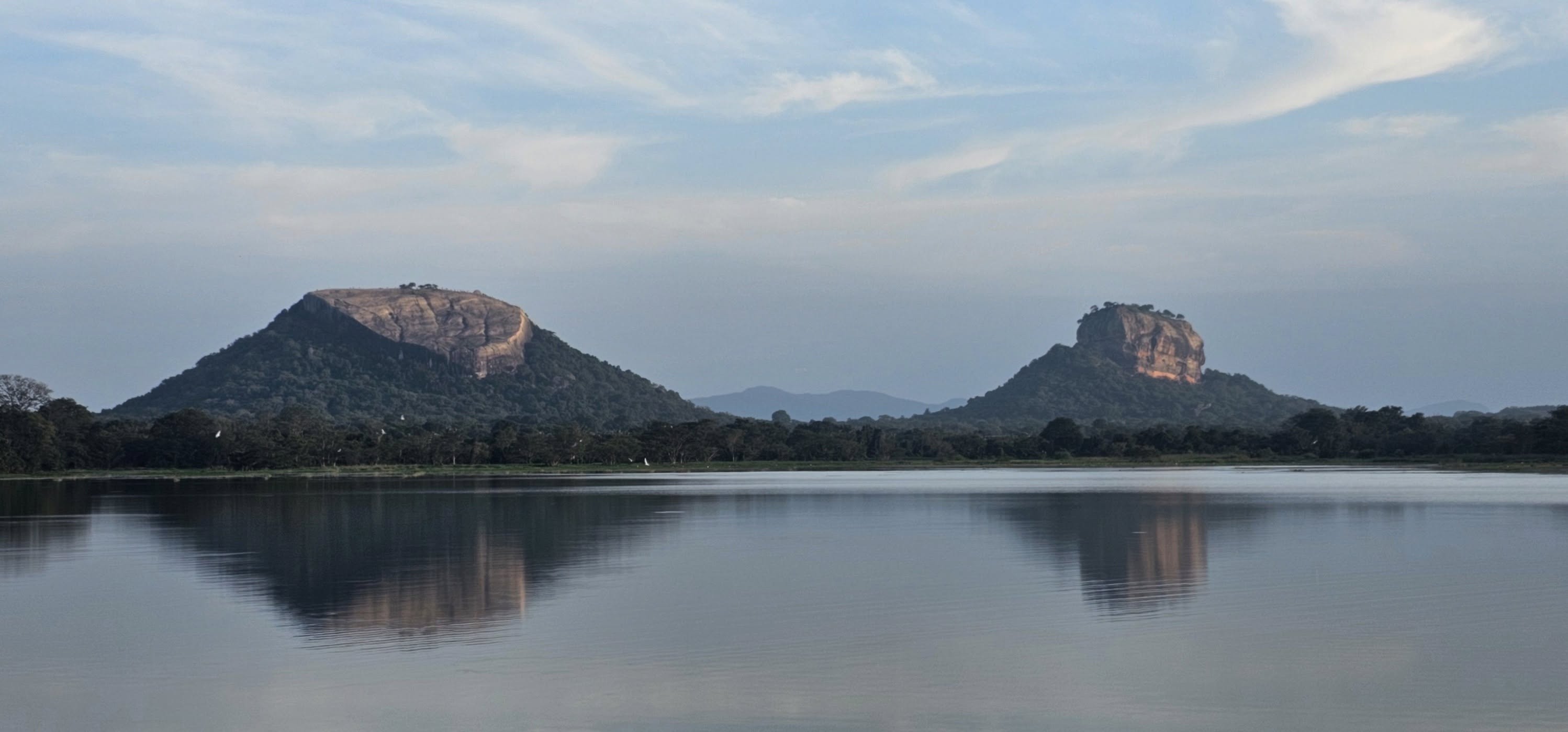 Sigiriya and Pidurangala rocks reflected in a lake at dawn